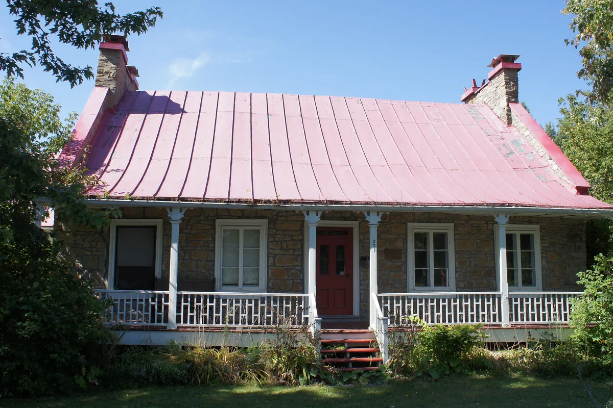 La maison Abraham-Dubois, maison de pierre au toit de tôle rouge et à la galerie blanche, à Boisbriand